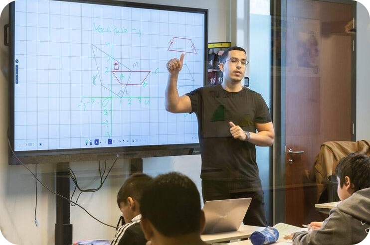 Teacher pointing at interactive whiteboard, teaching a classroom